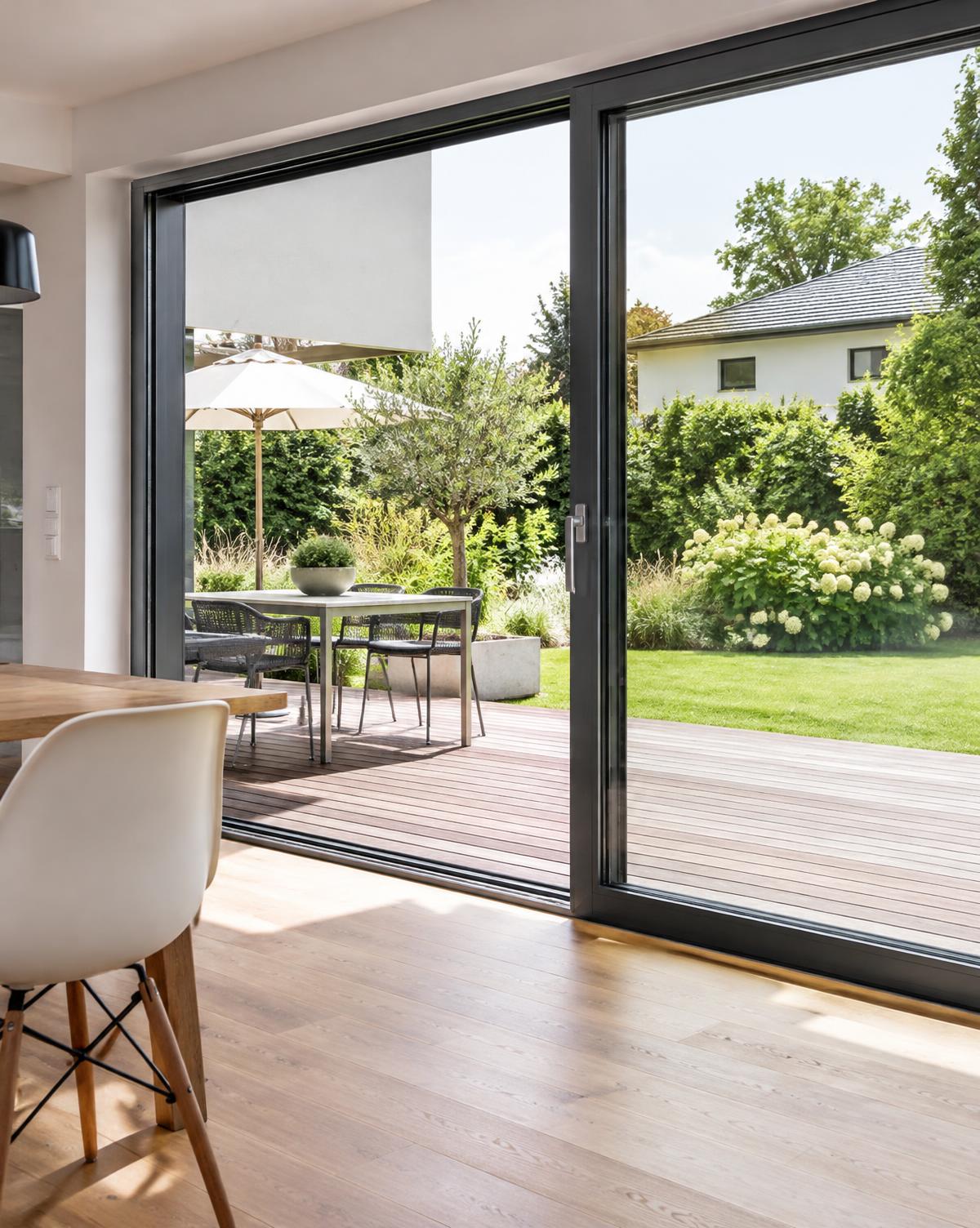 Große anthrazitfarbene Schiebetür mit Blick auf Terrasse und Garten